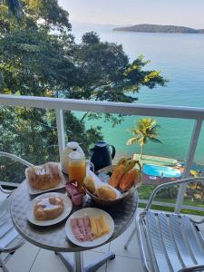 een dienblad met ontbijtproducten op een tafel op een balkon bij Ocean Green Flats in Angra dos Reis