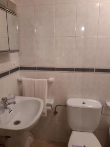 La salle de bains est pourvue de toilettes blanches et d'un lavabo. dans l'établissement Habitaciones CASA BRAIS, à Barreiros