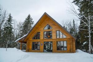 una cabaña de madera en el bosque en la nieve en Le Chalet Bois Rond Relax, en Saint-Tite-des-Caps