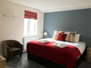 a bedroom with a bed with a red blanket and a chair at Botley Townhouse in Oxford