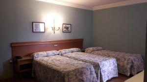 a room with three beds and a light on the wall at Hotel Juan Carlos I in Villarrobledo