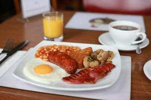 a plate of breakfast food with eggs sausage beans and coffee at Bridge Guest House in Tiverton