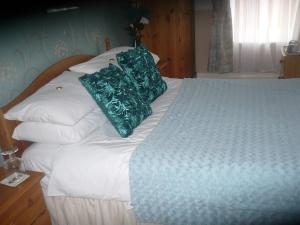 Una cama con almohadas verdes encima. en The Broadfield, en Bridlington 2 fotos más