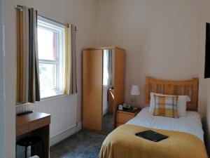 a bedroom with a bed and a desk and a window at Edendale House in Southport