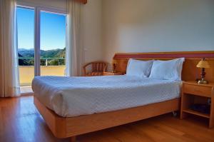 ein Schlafzimmer mit einem Bett und einem großen Fenster in der Unterkunft Hotel Miracastro in Castro Laboreiro