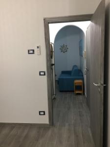 pasillo con puerta a una habitación con sofá azul en FILOMENA HOME, en Scalea