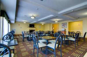 a restaurant with blue tables and chairs and yellow walls at Holiday Inn Express Hotel & Suites Kansas City Sports Complex, an IHG Hotel in Kansas City