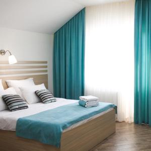 a bedroom with a bed with blue curtains at Timashevsk Rich Hotel in Timashevsk