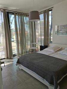 Un dormitorio con una cama grande y grandes ventanales. en Shekvetili Vacation Home, en Shekhvetili