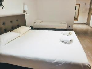 a large white bed in a room with two beds at Hôtel Casa Mea in Bastia