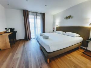 a bedroom with a large white bed and a desk at Hôtel Casa Mea in Bastia