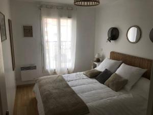 une chambre avec un lit avec des draps blancs et une fenêtre dans l'établissement ARCACHON appartement T2 51M2 et parking privatif en sous sol, à Arcachon