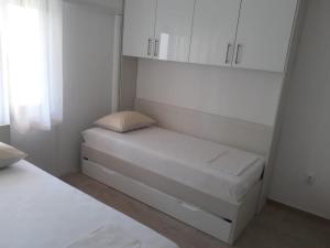 a small room with a bed and white cabinets at Apartments Jurlina in Seline