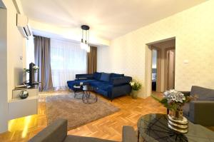 a living room with a blue couch and a table at Sky lux apartman in Gornji Milanovac