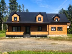 a large wooden house with a black roof at Chalet Diel in Herouxville