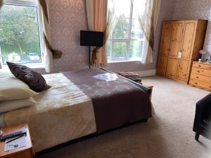a bedroom with a large bed and two windows at The Fairmile in Lytham St Annes