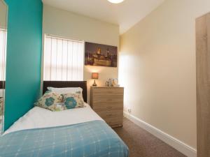 a bedroom with a bed and a blue wall at Townhouse @ Minshull New Road Crewe in Crewe