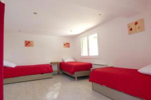 Habitación con 2 camas con sábanas rojas y ventana en Gites Bel Air de Rosette, en Bergerac