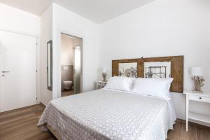 um quarto branco com uma cama branca e uma cabeceira de cama em madeira em Ca' Mira - Room&Breakfast em Savio di Ravenna