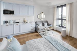 a white living room with a couch and a kitchen at Apartament Golden Place 2 in Kraków