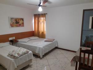 sypialnia z 2 łóżkami i wentylatorem sufitowym w obiekcie Psiu Lanches e Hotel Veraneio w mieście Posse