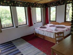 a bedroom with a bed in a room with windows at GUEST HOUSE ELENA in Kosovo