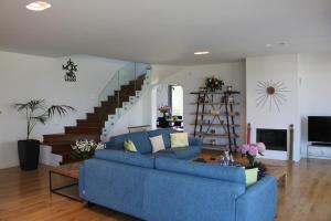 ein Wohnzimmer mit einem blauen Sofa und einer Treppe in der Unterkunft Villa Ren in Dassia