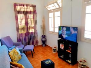 a living room with a blue couch and a flat screen tv at Sea Breeze Villa - in front of the beach in Câmara de Lobos