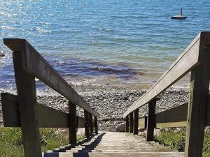 a wooden staircase leading to the beach with a boat in the water at 4 person holiday home in Slagelse in Slagelse