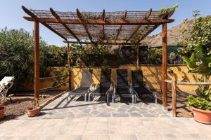 a patio with chairs and a wooden pergola at La Almendra in San Bartolomé