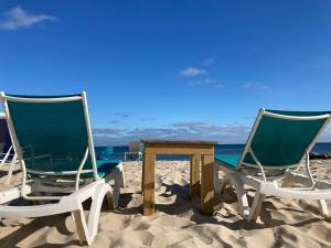 2 sillas y una mesa en la playa en By The Sea Guests Bed & Breakfast and Suites en Dennis Port