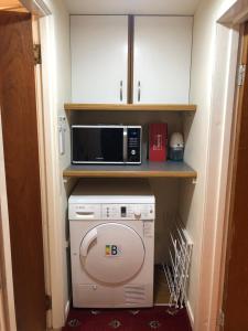 a small kitchen with a microwave and a washer at Cosy holiday home, Scalloway, Shetland. in Scalloway