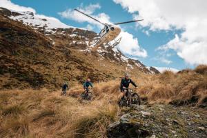 three people riding bikes on a hill with a helicopter at The Spire Hotel in Queenstown