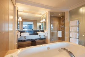 a bathroom with a tub and a large mirror at The Spire Hotel in Queenstown