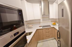 cocina con armarios blancos y TV grande en Apartamento Vip la Barrosa, en Chiclana de la Frontera