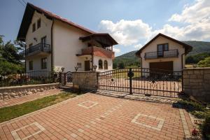 a house with a gate and a brick driveway at Apartman Lucija & Luka in Otočac