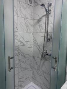 ein Bad mit einer Dusche und Marmorfliesen in der Unterkunft Затишні апартаменти подобово,центр in Ternopil