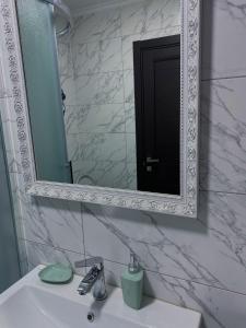baño con espejo y lavabo con lavamanos en Затишні апартаменти подобово,центр, en Ternopilʼ