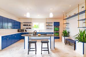una cocina con armarios azules y una gran isla con taburetes en Villa Northwinds - At Orange Hill - Private Pool, en Nassau
