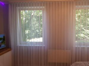 a bedroom with a window with white curtains at Apartament Polonia in Kołobrzeg