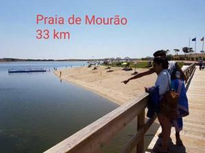 a man and a woman standing on a pier near the beach at Hotel Passagem do Sol in Moura