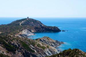 an island in the ocean with a lighthouse on it at Acquamaris Tuerredda in Teulada