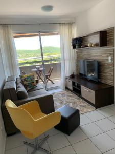 a living room with a couch and a television and a chair at Natal Verano Ponta Negra in Natal