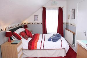 a bedroom with a bed with red curtains and a window at The Ryecroft in Great Yarmouth