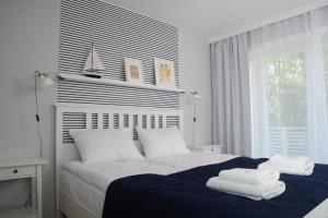 een witte slaapkamer met een bed met handdoeken erop bij Przystań na Zagórzu - Apartamenty nad jeziorem in Drezdenko
