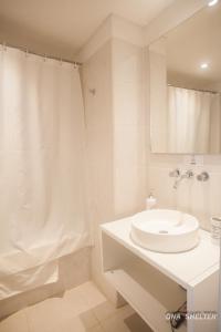 Baño blanco con lavabo y cortina de ducha en Ona Shelter en Ushuaia