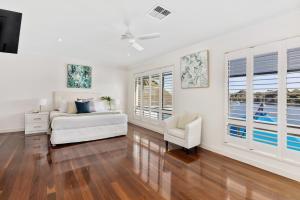 a white room with a bed and a chair and windows at 20 Noosa Parade, Noosa Heads in Noosa Heads