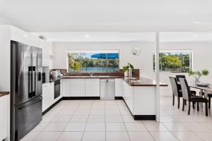 a kitchen with white appliances and a table with chairs at 20 Noosa Parade, Noosa Heads in Noosa Heads