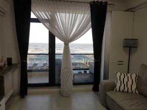 a living room with a large window with a view of the ocean at PANORAMIS PROMENADA-LARISA in Mamaia Sat/Năvodari