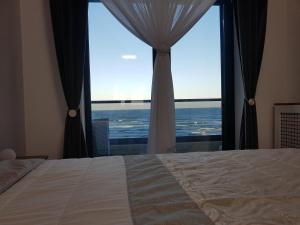 a bedroom with a bed and a large window at PANORAMIS PROMENADA-LARISA in Mamaia Sat/Năvodari